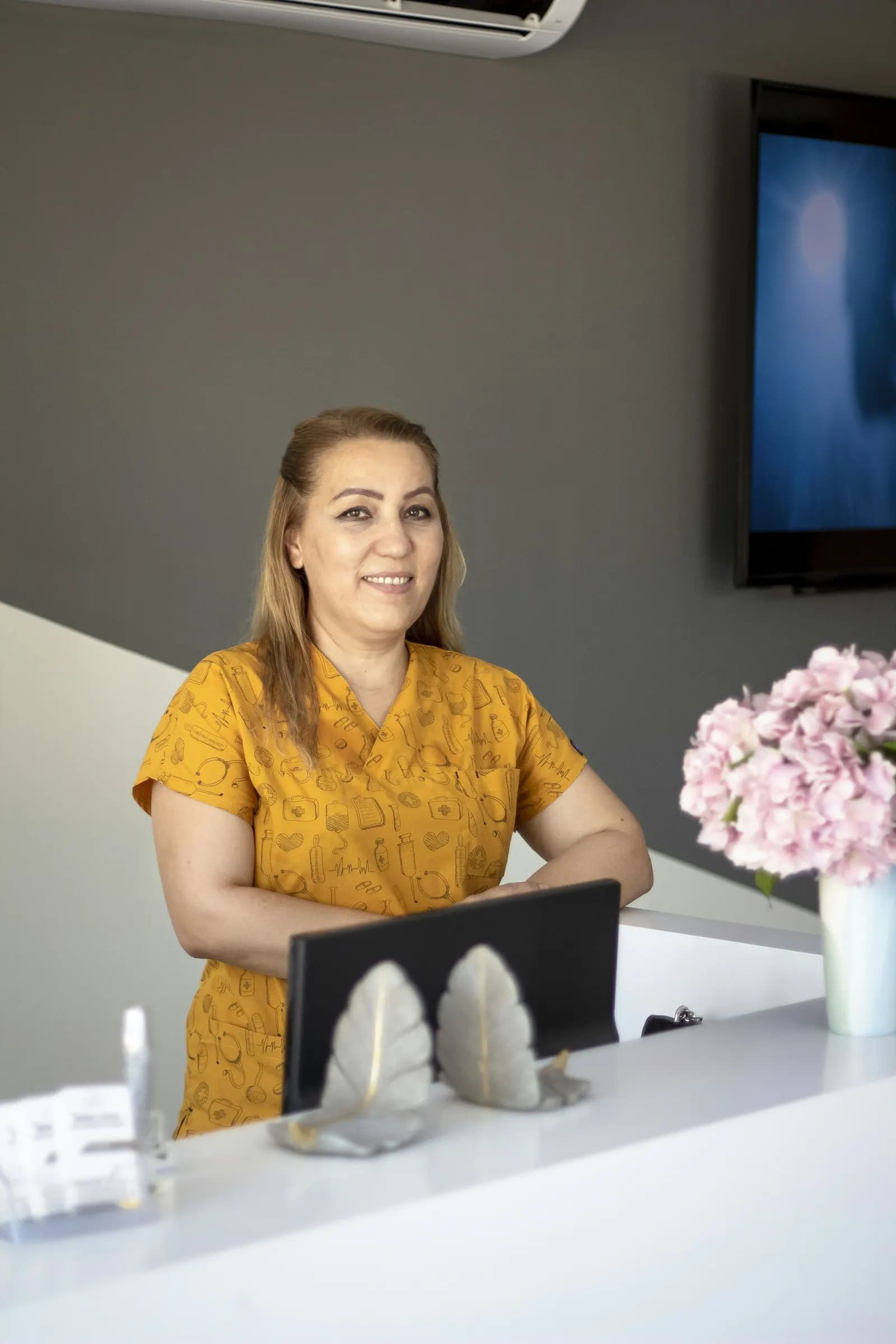 Recepcionista de una clínica atendiendo en el mostrador